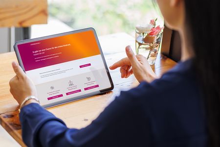 Frau betrachtet die Startseite der Himbeerrot-Website auf einem Tablet.