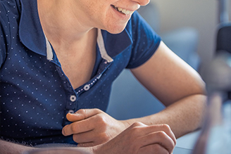 Blonde Frau in einem blauen Poloshirt liest einen Newsletter auf dem Rechner.