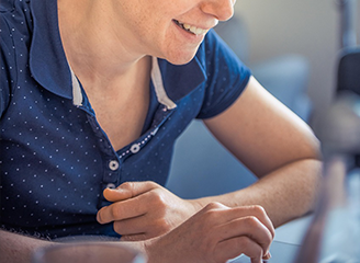 Blonde Frau in einem blauen Poloshirt liest einen Newsletter auf dem Rechner.